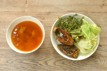fried snake head fish and egg stuffed climbing wattle in spicy sour soup on plate