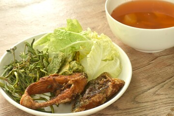 fried snake head fish and egg stuffed climbing wattle in spicy sour soup on plate