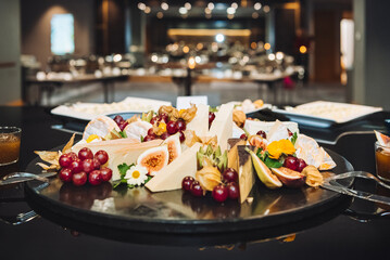 Cheese plate and fruits. Serving on a black platter