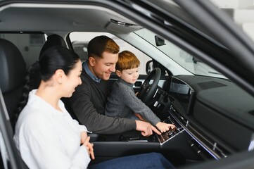 A joyful family sitting inside a new car at a dealership