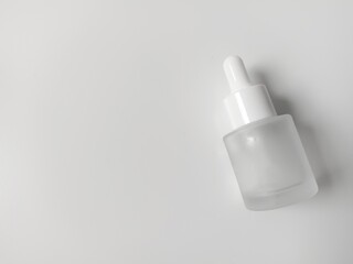 Glass bottle with clear and white colored pippet. Isolated white background, closeup