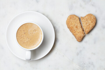 Cup of coffee with broken heart shaped cookies. Top view