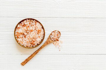 Coarse pink salt in wooden bowl and spoon and spilled salt. Cooking or spa concept