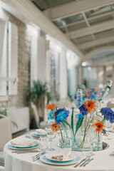 Colorful flowers in vases stand on a set table in a restaurant