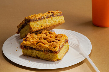 Homemade jam and crumb cake on a sandy background on disposable tableware. Quick preparation of homemade food and a calorie-rich dessert for a picnic.
