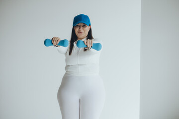 Big fat large woman model in sportswear doing sports on yoga and pilates mat ready for workout in home fitness gym.