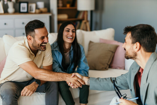 Happy couple shaking hands with financial advisor during therapy session