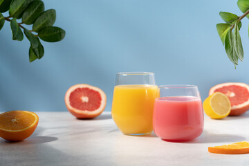 Orange and grapefruit refreshing drink on blue background. Smoothie, juice or citrus cocktail side view
