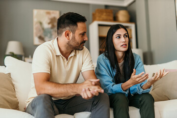 Naklejka premium Young couple arguing while sitting on sofa at home