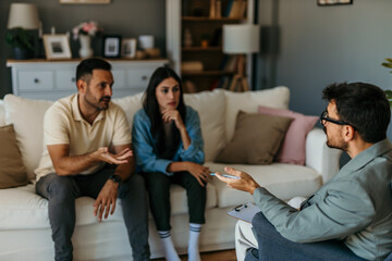 Couple arguing during therapy session with psychologist taking notes