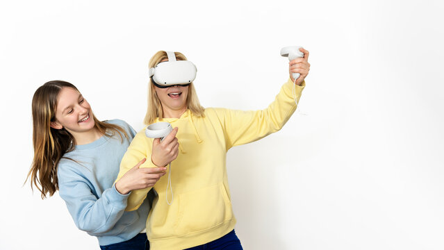 Excited mother experiencing virtual reality while her daughter enjoys watching her play - Powered by Adobe