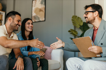 Financial advisor shaking hands with a happy couple during a meeting