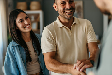 Happy couple shaking hands with financial advisor during a meeting at home