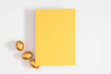 Happy Easter day, greeting card, blank paper and golden Easter eggs on a white background. Top view.