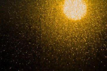 Blurred bokeh light sparkle on golden black background