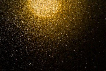 Blurred bokeh light sparkle on golden black background