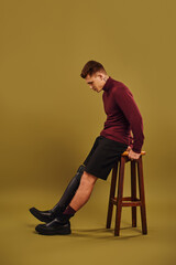 Handsome young man showcases modern fashion with prosthetic leg in studio setting