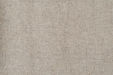 Natural linen fabric close-up: texture, fibers, and weave in neutral beige tones.