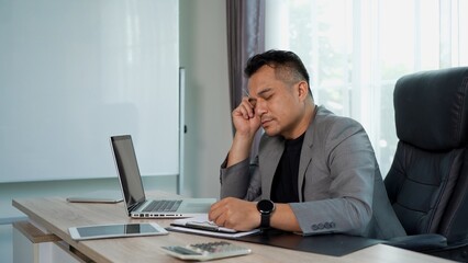Fototapeta premium Thoughtful Asian Businessman working on laptop on Desk at office