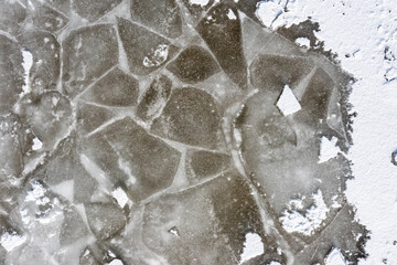 The texture of a frozen lake and pieces of floating ice in the water. Winter landscape from a drone.