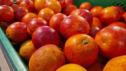 Sicilian oranges for sale in a supermarket. Citrus fruits in plastic boxes, close-up. Ripe oranges in a store. Ripe, juicy, bright oranges. Heaps of citrus fruits for sale at the market