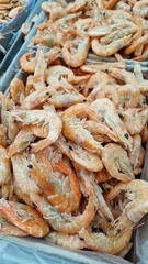 Frozen cooked shrimps in supermarket or grocery store, close-up. Seafood. Many frozen unpeeled shrimps