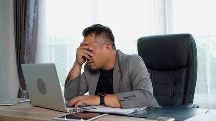 Fototapeta premium Businessman feel disappointed while working on laptop computer and documents