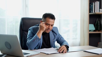 Naklejka premium Young businessman working with document and laptop on desk at office