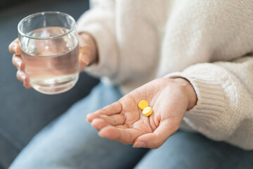 Close-up hands of person holding painkiller pills and water