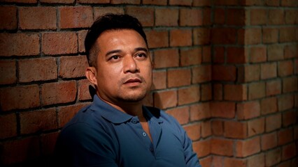Sadness Man sits leaning Against a Brick Wall with Expressing Distress