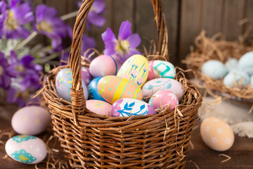 Decorated Easter eggs in a basket with purple daisies