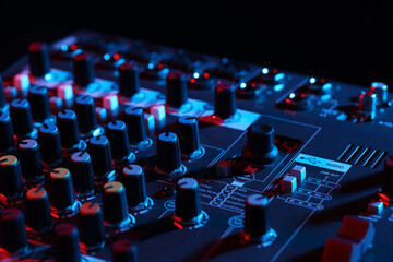 Professional mixing console on black background in neon lights, closeup