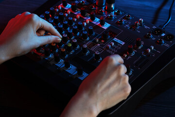 Woman working with professional mixing console at wooden table, closeup