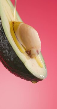 tasty avocado juice that is healthy and nutritious is pouring down from above on slice of avocado