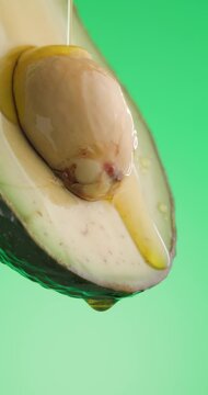 delicious avocado juice from freshly cut avocado fruit is pouring down in slow motion on green background