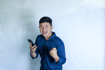 feeling happy excited modern successful young man holding the phone and raising his hand 