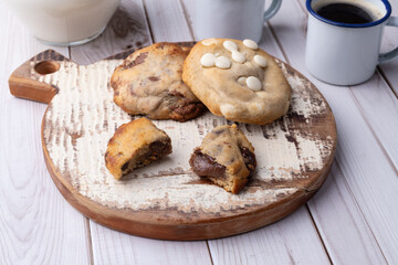 Assorted chocolate cookies on a board with milk and coffee