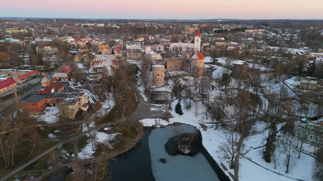 Cesis City, Latvia Aerial View With Medieval St. John&rsquo;s Church and Ruins of the Beautiful Castle a Residence of the Livonian Order in the Middle Ages. Winter Evening Landscape at Sunset. City in snow
