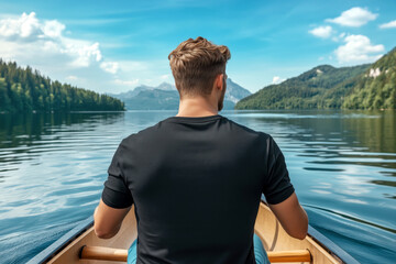Fototapeta premium Young man wearing short sleeve black tee is paddling canoe on calm lake. Men's regular fit сrewneck t-shirt mockup, back side view. Holiday, vacation outdoors lifestyle basic tee template