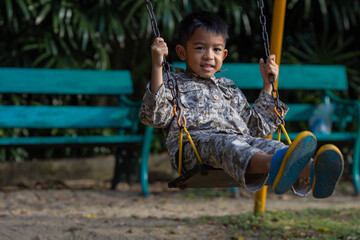 Little kindergarten asian boy enjoy play swing bar outdoor playground happy time