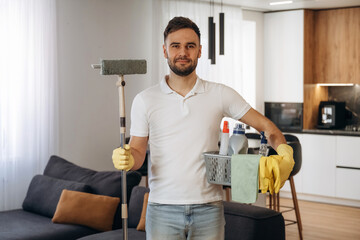 Positive facial expression. Male professional cleaning service worker is domestic room