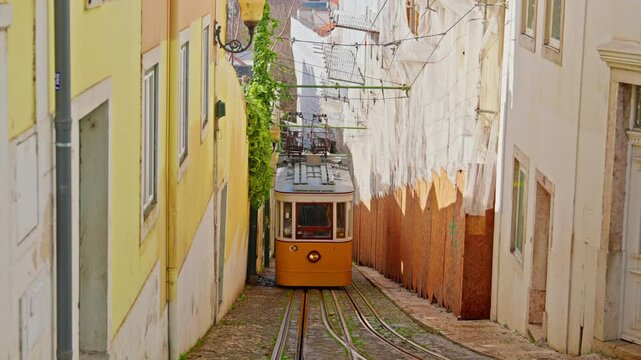 Lisbon, Portugal, 26 February 2025: The old yellow tram, funicular on the narrow street in Lisbon