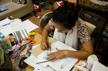 Thai designer women drawing and design pattern fashion on paper for make mood board and cut clothes