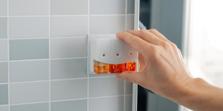 man plugging a plug-in air freshener