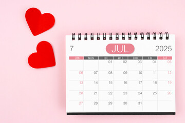 Red heart with July 2025 desk calendar on pink background.