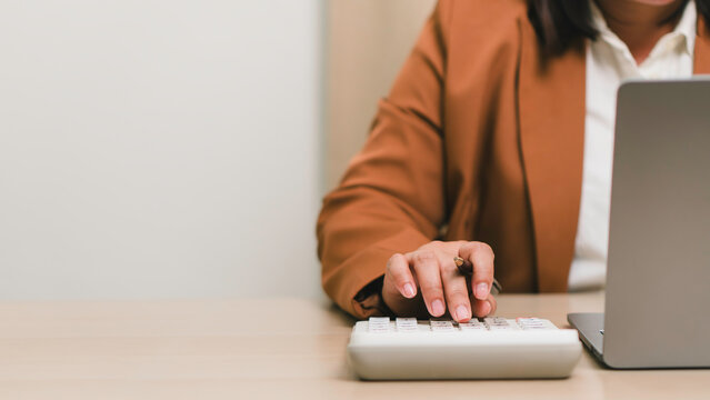 Financial accounting and business budgeting concept. Professional calculating business expenses with calculator and laptop, illustrating finance management, audit, and economic planning.