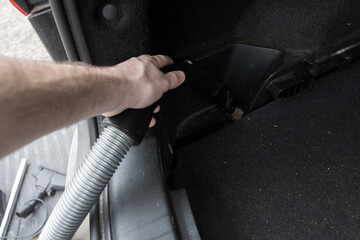 Close-up of a vacuum cleaning a dirty car mat near the pedals, ensuring a spotless interior. Great for car detailing, cleanliness, and auto care tips.