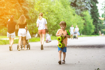 A happy child with toy in a sunny park, surrounded by people walking and enjoying nature. Perfect for family, childhood, and outdoor activities themes.