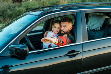 Father and daughter enjoying a road trip, pointing at something outside the car window, creating a heartwarming moment of connection and shared experience