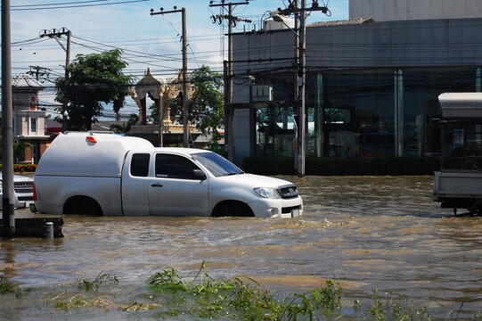 Thai people riding motorcycle and driving car on street while water flood or inundation road with vehicle busy jam traffic highway at countryside rural city on October 20, 2011 in Nonthaburi, Thailand